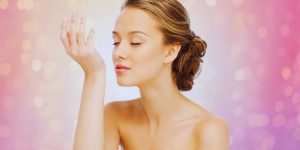 Mulher cheirando o próprio pulso com expressão de agrado