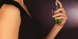 Mulher de vestido preto passando perfume