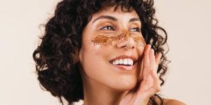 Close no rosto de mulher sorridente passando produto na pele