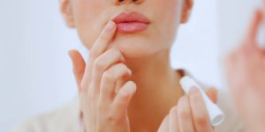 Close no rosto de uma mulher passando hidratante labial