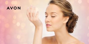 Mulher cheirando o próprio pulso com ar de satisfação; ao lado, uma logo da Avon