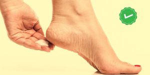 Close em um pé feminino no qual está sendo passado um creme no calcanhar